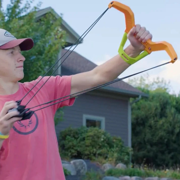 Person using Spunky Pup Bow Blaster Launcher to launch tennis ball outdoors