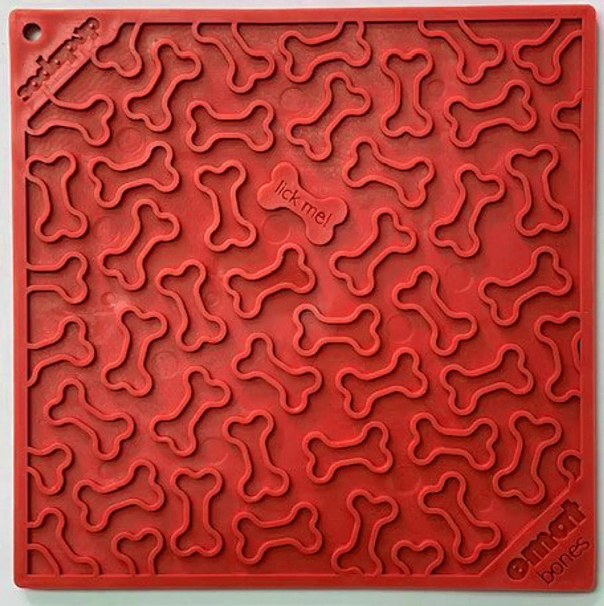 Red SodaPup Bones silicone lick mat with raised bone texture and 'lick me' center