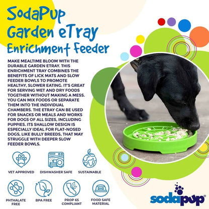 Black dog eating from green SodaPup garden enrichment feeder on deck
