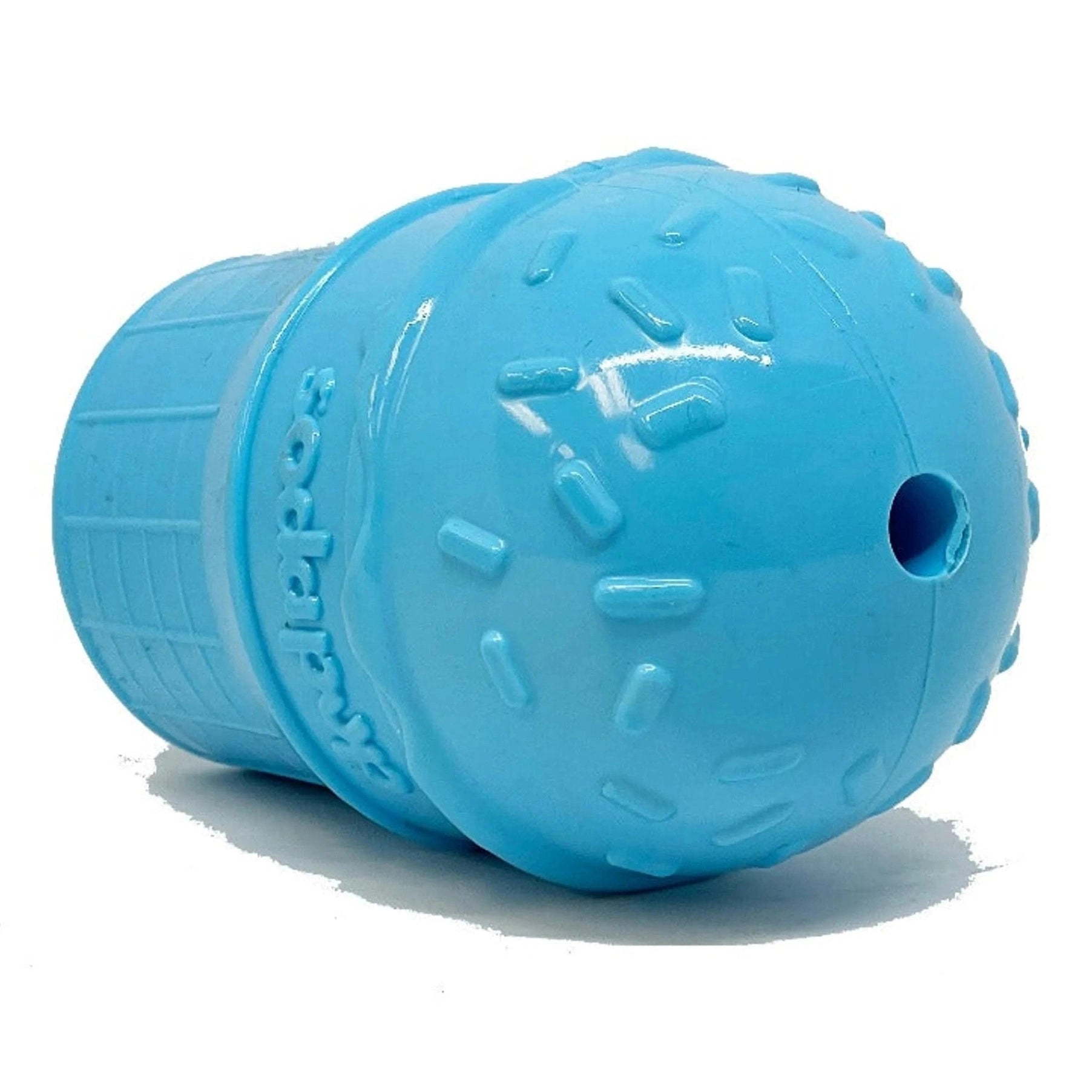 Side view of blue rubber dog toy showing circular treat opening and embossed brand logo