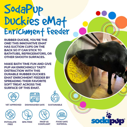 Black dog licking yellow duck pattern enrichment feeder on fridge