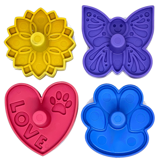 Four colorful plastic treat dispenser accessories featuring smiley butterfly, sunflower, heart with LOVE text, and paw shapes for upright freezing